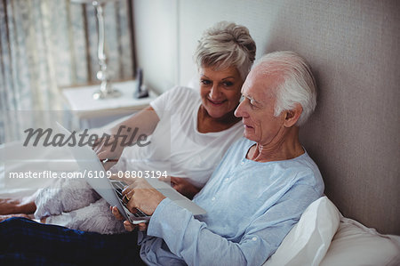 Senior couple using laptop on bed in bed room