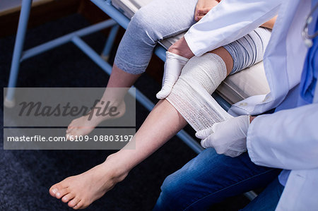Doctor putting bandage on injured leg of patient in hospital Doctor putting bandage on injured leg of patient in hospital
