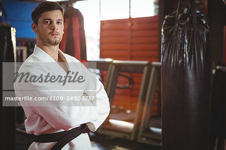Karate player standing with arms crossed in fitness studio