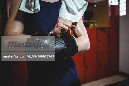 Boxer wearing boxing gloves in locker room at fitness studio