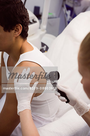 Doctor removing mole with laser treatment in clinic