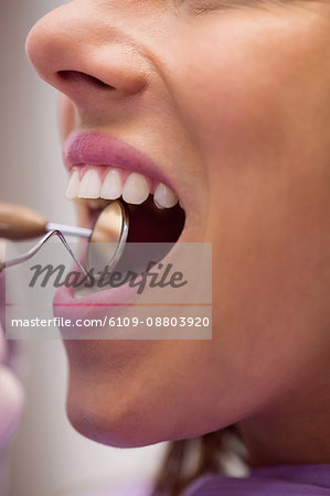 Close-up of dentist examining a female patient with tools at dental clinic