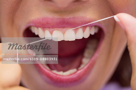 Close-up of female patient flossing her teeth in dental clinic