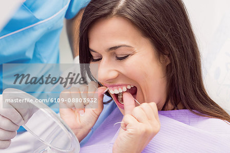 Female patient flossing her teeth in dental clinic