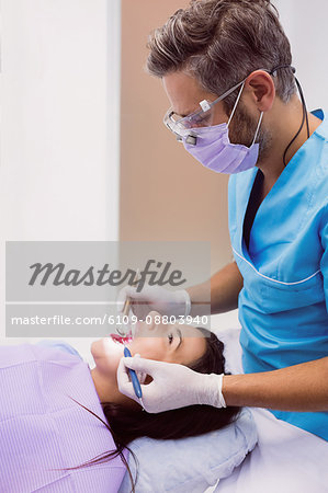 Dentist examining a female patient with tools at dental clinic 4k