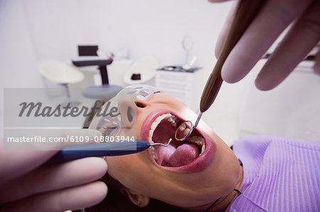 Dentist examining a female patient with tools at dental clinic 4k