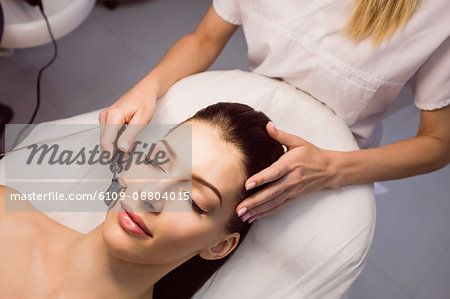 Dermatologist performing laser hair removal on patient face in clinic