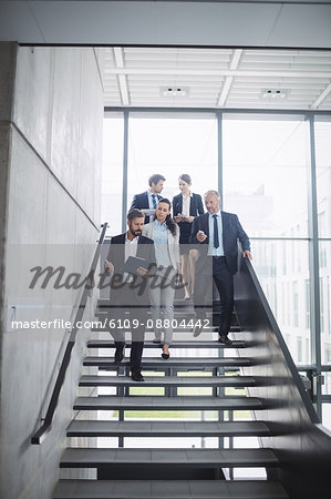 Confident businesspeople standing on staircase in office
