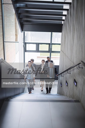 Portrait of confident businesspeople standing on staircase in office