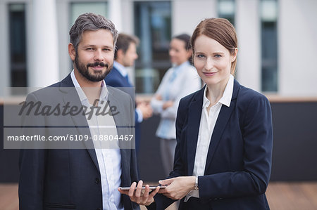 Portrait of businesspeople holding digital tablet in office