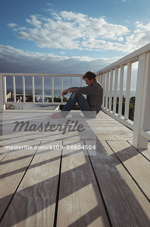 Side view of a worried man sitting on balcony