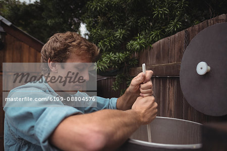 Man stirring beer in work while making beer at home brewery