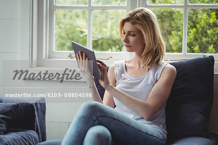 Beautiful woman using digital tablet in living room at home