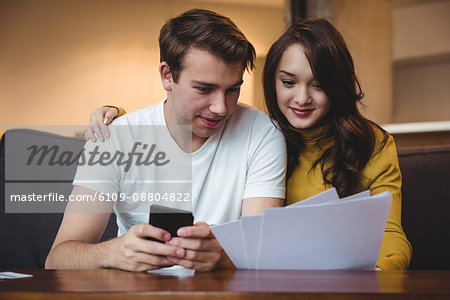 Couple discussing with financial documents and calculator in living room at home