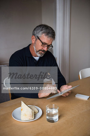 Man sitting at table and using digital tablet at home