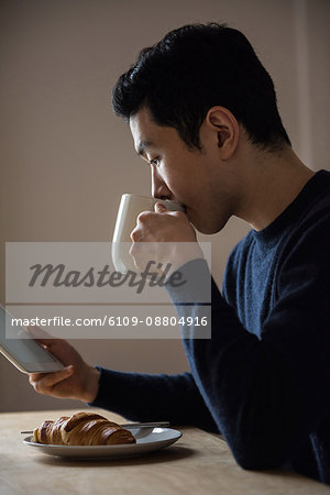 Man using digital tablet while having breakfast at home