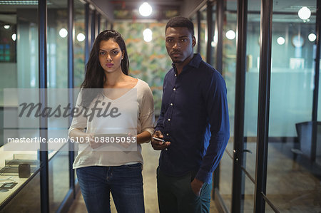 Portrait of businessman and a colleague holding digital tablet and mobile phone in office