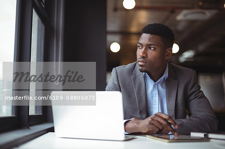 Thoughtful businessman looking at window in office