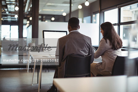 Businessman and a colleague working over computer in office