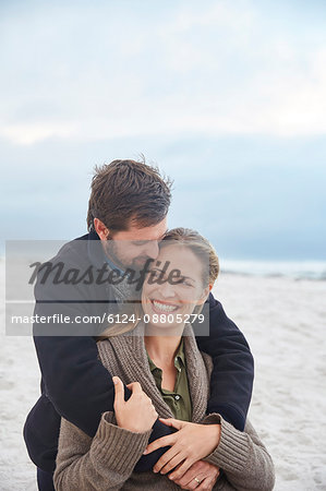 Smiling affectionate couple hugging on winter beach