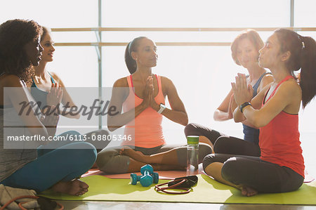Serene women meditating in yoga class gym studio