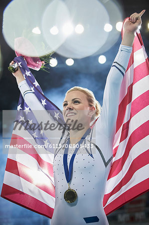 Smiling female gymnast celebrating victory holding American flag