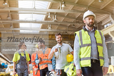 Steel workers talking and walking on coffee break in factory