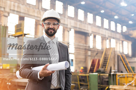 Portrait smiling manager with blueprints in steel factory