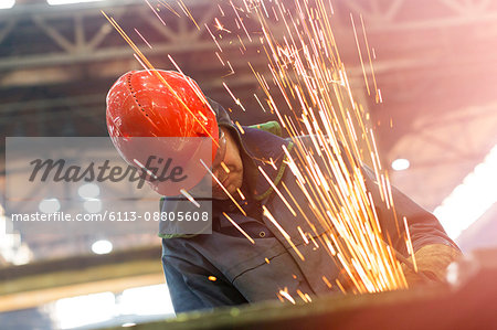 Welder using welding torch with sparks in steel factory