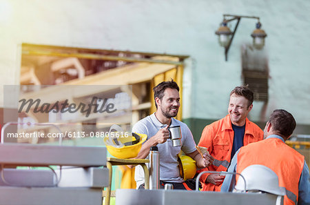 Smiling steel workers enjoying coffee break ins factory