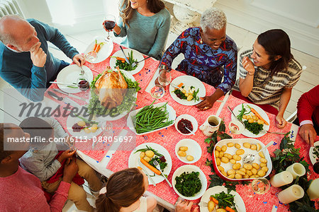 Overhead view multi-ethnic multi-generation family enjoying Christmas dinner at table