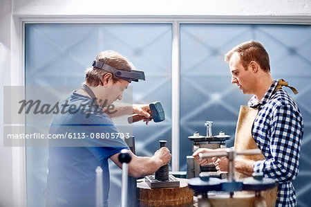 Jewelers using equipment in workshop