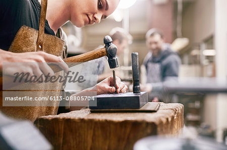 Jeweler using hammer in workshop