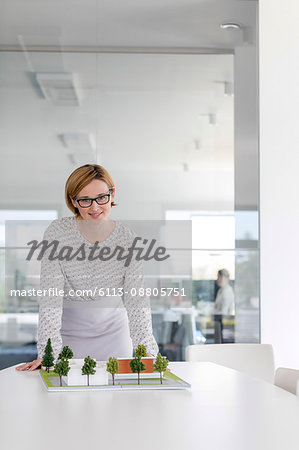 Portrait confident female architect with model in conference room