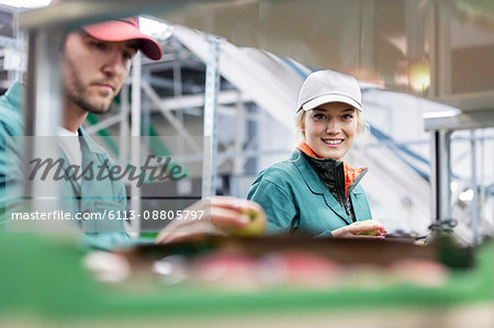 Portrait smiling female worker inspecting apples in food processing plant