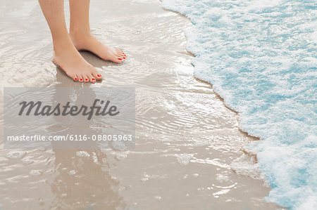 Woman's feet standing in surf at the beach