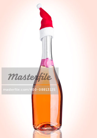 Bottle of pink rose champagne with santa hat on pink background