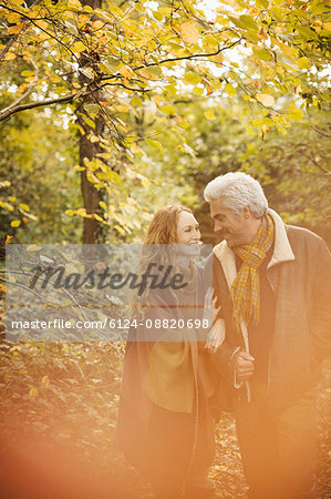 Affectionate couple walking arm in arm in autumn woods