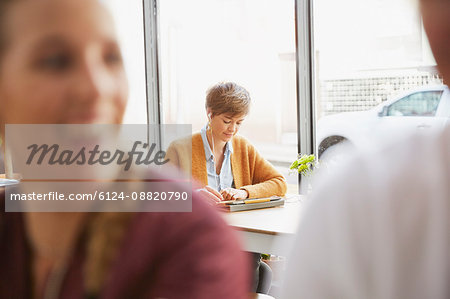 Woman with headphones using digital tablet at cafe window