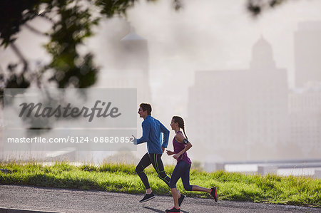 Runner couple running on sunny urban city street