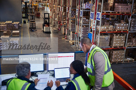 Managers working meeting at laptop and computers in distribution warehouse