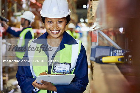 Portrait smiling female worker with clipboard in distribution warehouse