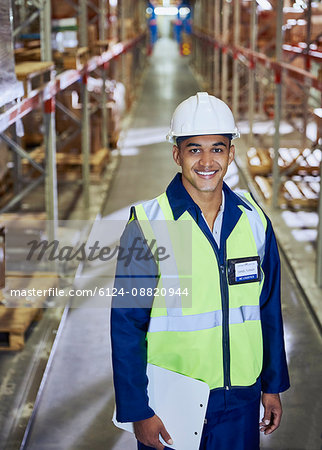 Portrait smiling worker with clipboard in distribution warehouse aisle