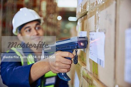 Worker with scanner scanning barcode on box in distribution warehouse