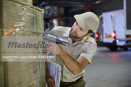 Truck driver worker with scanner scanning pallet of boxes in distribution warehouse