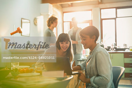 Young women roommates using laptop at table