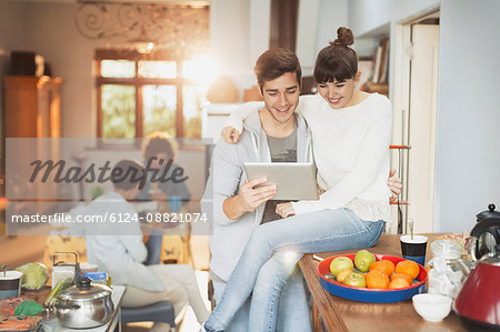 Smiling young couple using digital tablet in kitchen