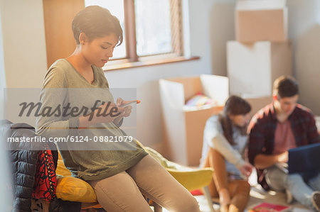 Young woman texting with cell phone in new apartment