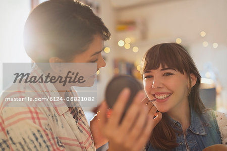 Young women friends applying makeup