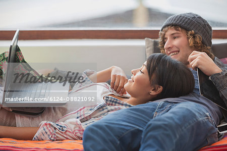 Young couple relaxing laying using laptop Young couple relaxing laying using laptop